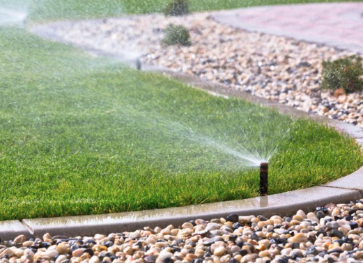 Modern irrigation system with water sprinkler on green lawn